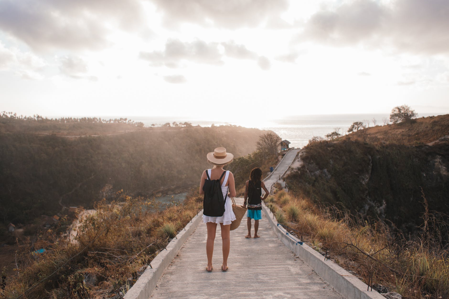 unrecognizable mother with daughter contemplating shiny sky from walkway