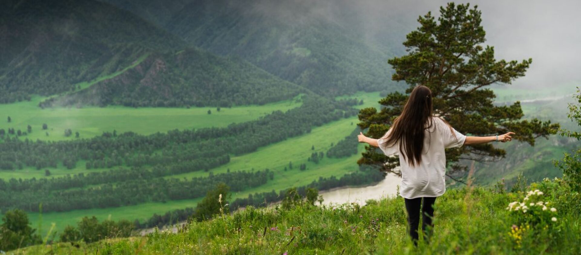A woman stands amidst the scenic greenery of Chemal, Altai Republic, Russia.